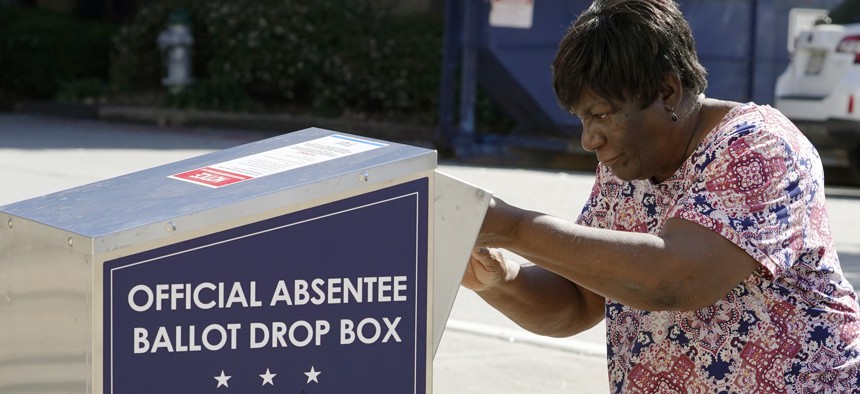 In this Oct. 19, 2020 file photo, a voter drops their ballot off during early voting in Athens, Ga.