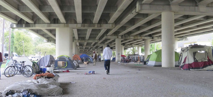 Individuals walk around a homeless encampment near downtown Houston, Texas.