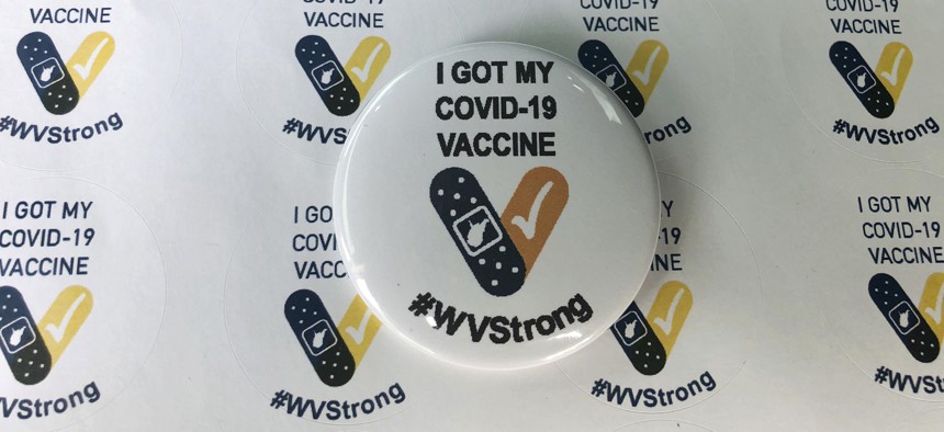 Stickers and a button given to people who receive their COVID-19 vaccines are displayed Thursday, Jan. 14, 2021, at the National Guard Armory in Charleston, W.Va. 