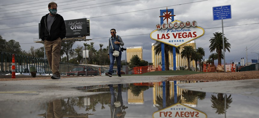 People wearing face masks visit the usually crowded "Welcome to Fabulous Las Vegas Nevada" sign amid the coronavirus outbreak along the Las Vegas Strip, Tuesday, April 7, 2020, in Las Vegas.