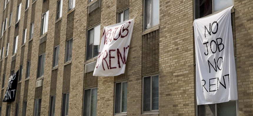 Signs reading "No Job No Rent" hang from the windows of an apartment building in Northwest Washington, Wednesday, May 20, 2020. 
