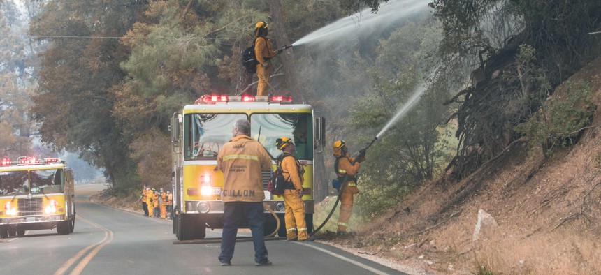 Firefighters clear land and throw water during a wildfire in California.