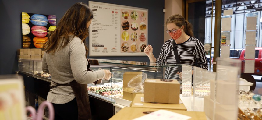 A customer interacts with shop owner Teresa Ging( left) while shopping for bakery goods in Sugar Bliss Bakery in Chicago's famed Loop, Tuesday, May 4, 2021. In many downtown areas where companies closed their offices and commuting ground to a halt, sandwich shops, bakeries and other small businesses are waiting with guarded optimism for their customers to return.