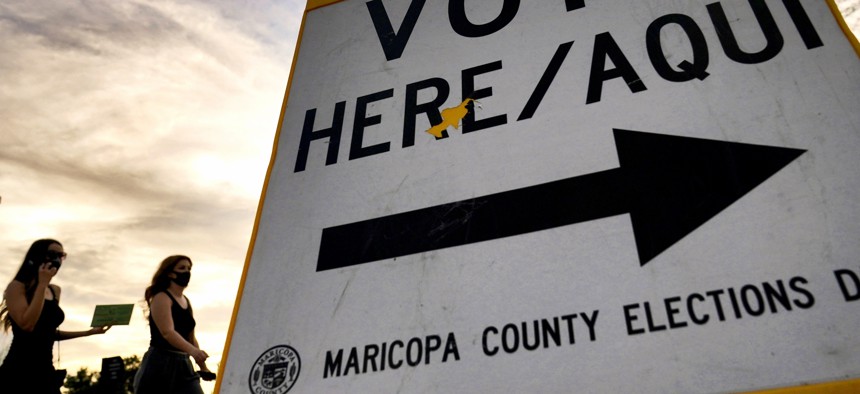 Voters deliver their ballot to a polling station in Tempe, Ariz. Arizona.