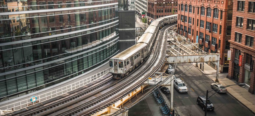 An L train passes over a city street in Chicago.