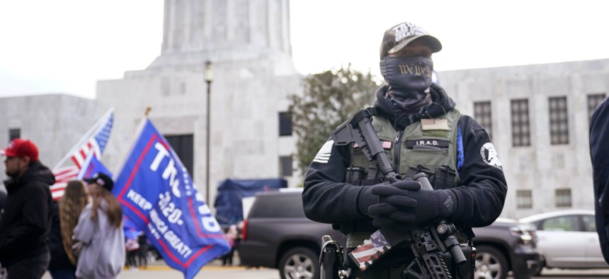 A man holds a gun as he stands in front of the Oregon State Capitol building in Salem, Ore.