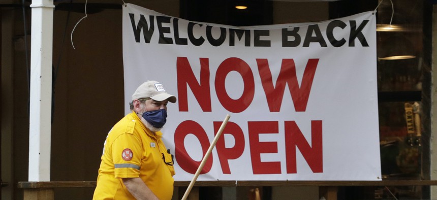 A worker passes a sign at a restaurant along the River Walk that has reopened in San Antonio.