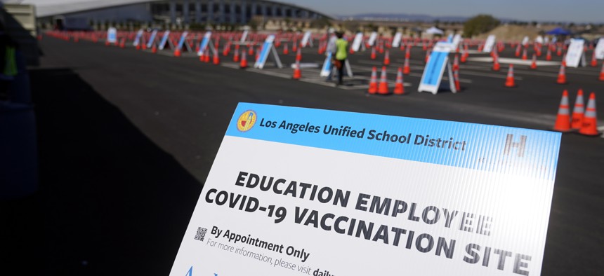 In this March 2, 2021, file photo, a sign is placed at a COVID-19 vaccination site for employees of the Los Angeles school district in the parking lot of SOFI Stadium in Inglewood, Calif.