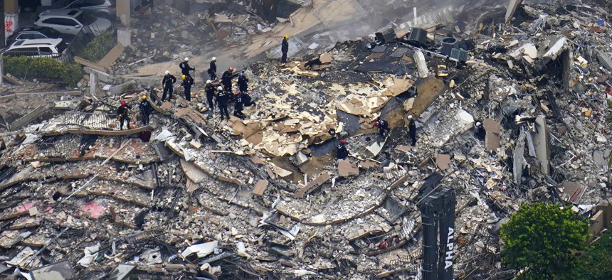 In this June 25, 2021, file photo, rescue workers search in the rubble at the Champlain Towers South Condo in Surfside, Fla.