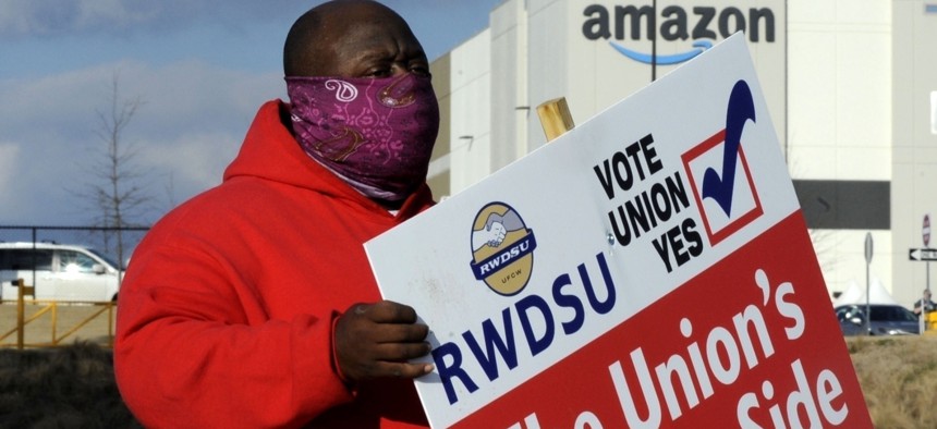 In this Tuesday, Feb. 9, 2021, file photo, Michael Foster of the Retail, Wholesale and Department Store Union holds a sign outside an Amazon facility where labor is trying to organize workers in Bessemer, Ala.