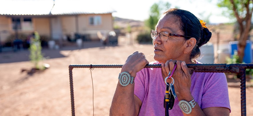 A Navajo woman standing by the gate of her home.