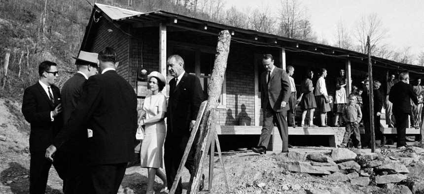 This April 24, 1964, file photo shows President Lyndon Johnson and his wife, Lady Bird, center left, leave the home in Inez, Ky., of Tom Fletcher, a father of eight who told Johnson he'd been out of work for nearly two years.