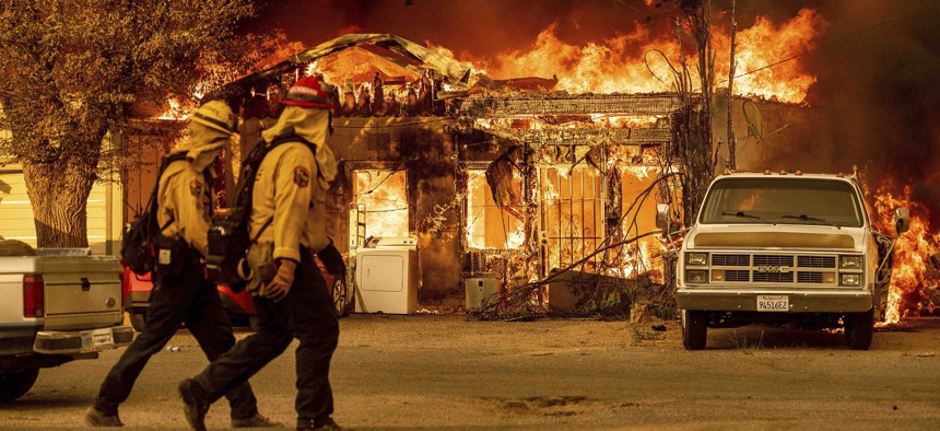 Firefighters pass a burning home as the Sugar Fire, part of the Beckwourth Complex Fire, tears through Doyle, Calif., on Saturday, July 10, 2021.