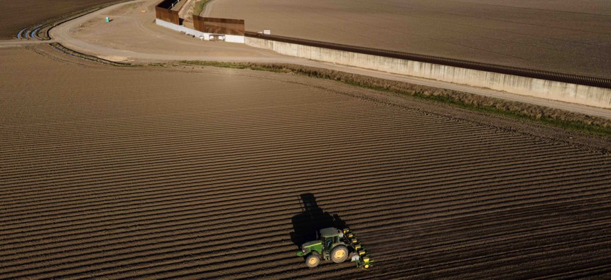 In this photo taken by a drone, the border wall construction is seen near farmland as a tractor plows a field, Friday, March 19, 2021, in Progreso, Texas. 