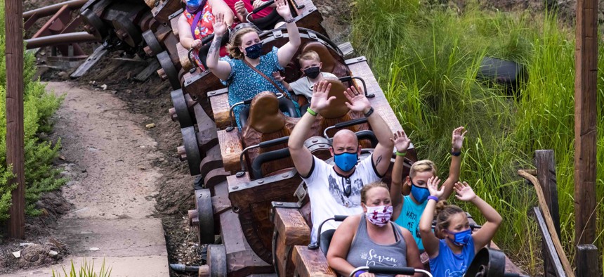Guests wear face masks due to the Covid-19 pandemic while riding the Seven Dwarfs Mine Train attraction at Walt Disney World Resort's Magic Kingdom on Thursday, August 13, 2020, in Lake Buena Vista, Fla.