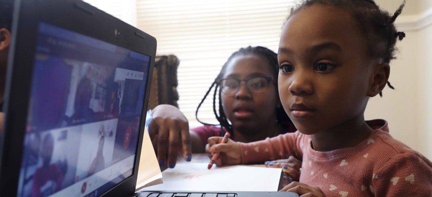 A student on the South Side of Chicago participates in virtual learning classes as her mother assists, in February 2021.
