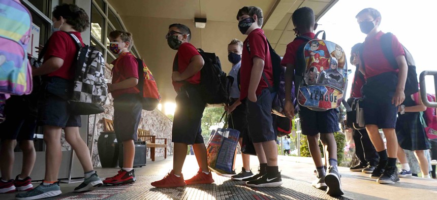 Wearing masks to prevent the spread of COVID-19, elementary school student line up to enter school for the first day of classes in Richardson, Texas, Tuesday, Aug. 17, 2021. 