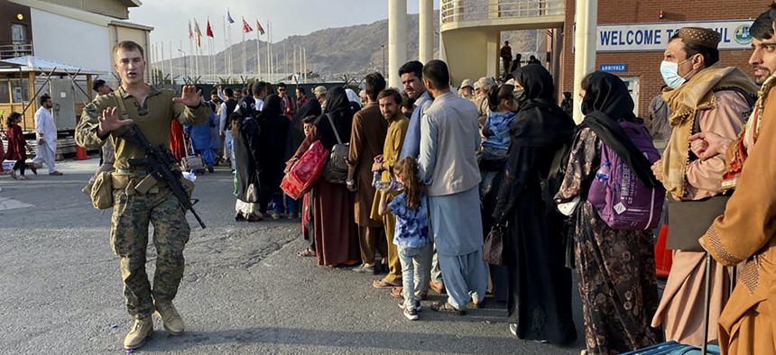 Afghan people queue up to board a U.S. military aircraft to leave Afghanistan, at the military airport in Kabul on August 19, 2021. 