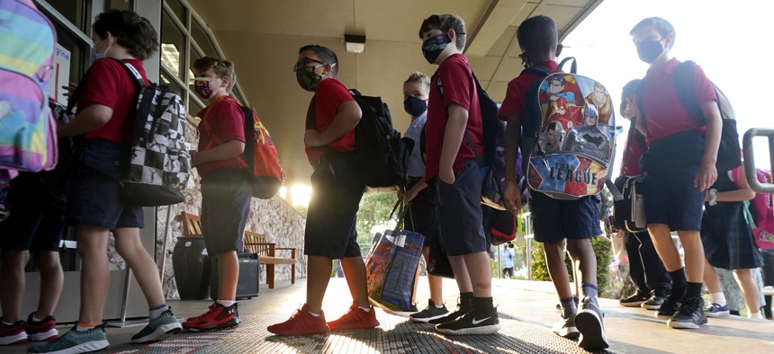 Wearing masks to prevent the spread of COVID-19, elementary school students line up to enter school for the first day of classes in Richardson, Texas, Tuesday, Aug. 17, 2021. Despite Texas Gov Greg Abbott's executive order banning mask mandates by local officials, the Richardson Independent School District and many others across the state are requiring masks for students. 