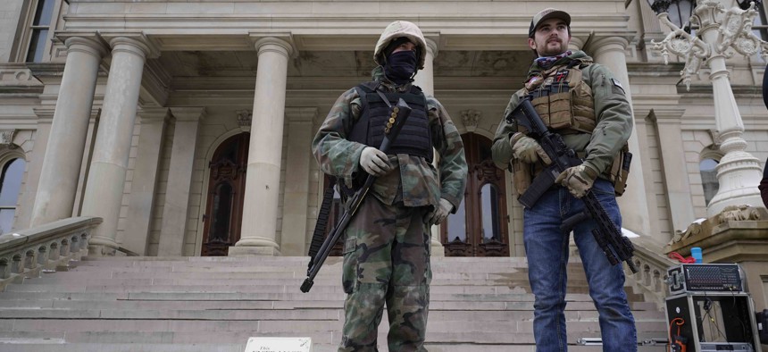 Armed men stand on the steps at the State Capitol after a rally in support of President Donald Trump in Lansing, Mich., Wednesday, Jan. 6, 2021. 