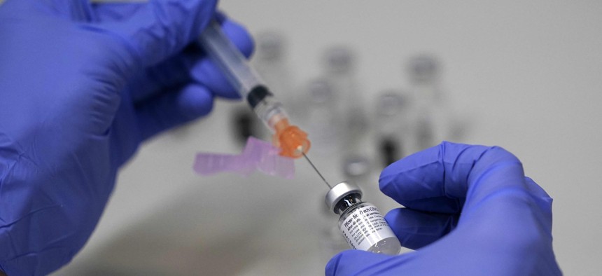 A pharmacy technician loads a syringe with Pfizer's COVID-19 vaccine, Tuesday, March 2, 2021, at a mass vaccination site at the Portland Expo in Portland, Maine. 