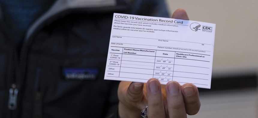 A nurse displays a real COVID-19 vaccination card.