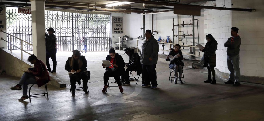 In this March 13, 2020, file photo, unionized hospitality workers wait in line in a basement garage to apply for unemployment benefits at the Hospitality Training Academy in Los Angeles. 