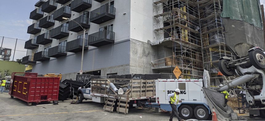 In this June 18, 2021, photo, construction workers finish the exterior of an apartment building downtown Los Angeles. 