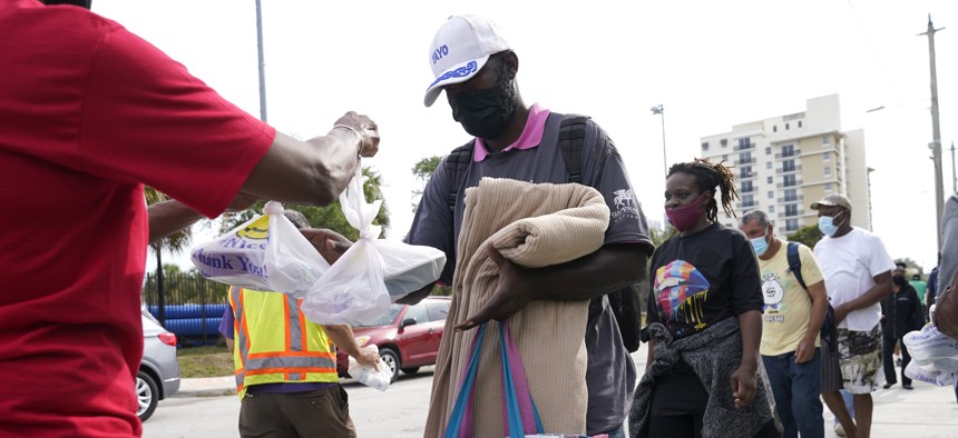 Residents stand in line for prepared meals during a food distribution held by the Overtown Youth Center and other local organizations, Monday, April 12, 2021, in the Overtown neighborhood in Miami.