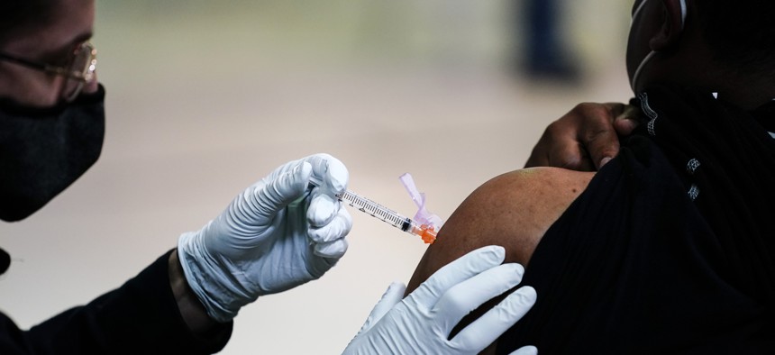 In this March 26, 2021, file photo, a member of the Philadelphia Fire Department administers the Johnson & Johnson COVID-19 vaccine to a person at a vaccination site at a Salvation Army location in Philadelphia. More Black Americans say they are open to taking the coronavirus vaccine amid campaigns to overcome a shared historical distrust of science and government.
