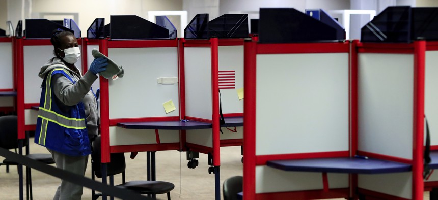 A poll worker cleans after a voter cast their ballot at the Hamilton County Board of Elections on Election Day, Tuesday, Nov. 3, 2020, in Norwood, Ohio.