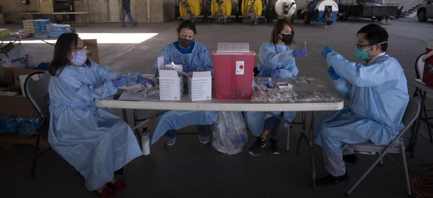 In this Jan. 21, 2021, file photo, health care workers prepare the Pfizer-BioNTech COVID-19 vaccine for farm workers at Tudor Ranch in Mecca, Calif. 