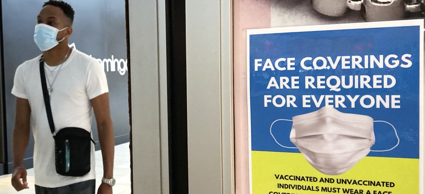 An information sign is displayed at a department store in Rosemont, Ill., Thursday, Aug. 26, 2021. Gov. J.B. Pritzker of Illinois announced on Thursday a new, stricter set of coronavirus restrictions, ordering a statewide indoor mask mandate and requiring that all educators be vaccinated or face regular testing. 