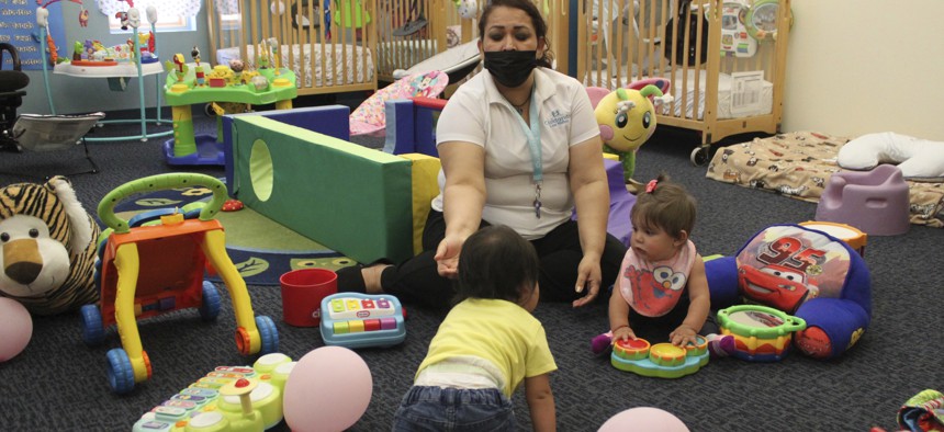 This May 2021 photo shows a teacher working with two infants at Cuidando Los Ninos in Albuquerque, N.M. The charity provides housing, child care and financial counseling for mothers.