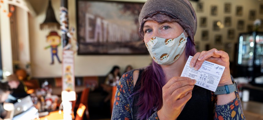 A patron shows her vaccination card before being allowed to sit inside the Fred 62 restaurant in the Los Feliz neighborhood of Los Angeles, Monday, Nov. 29, 2021.