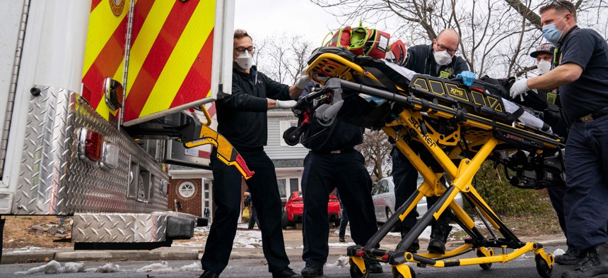 Firefighters and paramedics with Anne Arundel County Fire Department load a pediatric Covid-19 patient with underlying conditions who is in cardiac arrest into an ambulance after responding to a 911 emergency call on Jan. 17, 2022 in Glen Burnie, Maryland.