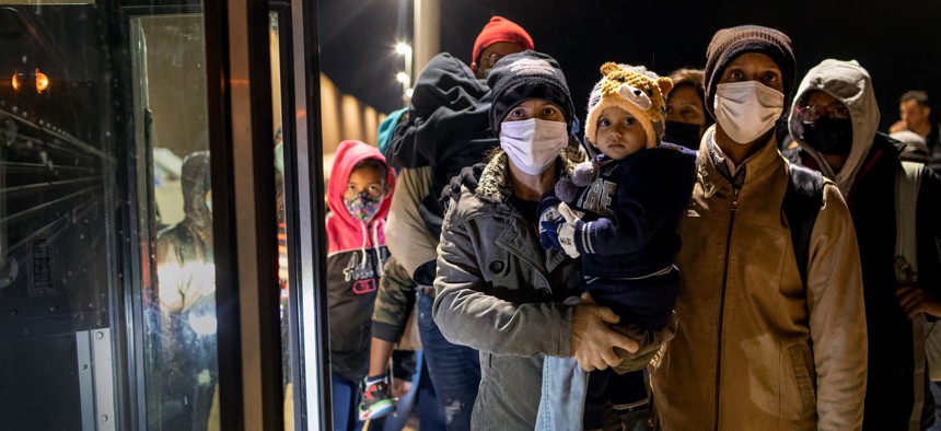 Immigrant families anxiously wait to board a bus for transport to a U.S. Border Patrol processing center on December 09, 2021 in Yuma, Arizona.
