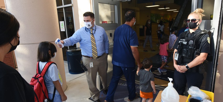Principal Nathan Hay performs temperature checks August 10, 2021 on students as they arrive on the first day of classes for the 2021-22 school year at Baldwin Park Elementary School. 