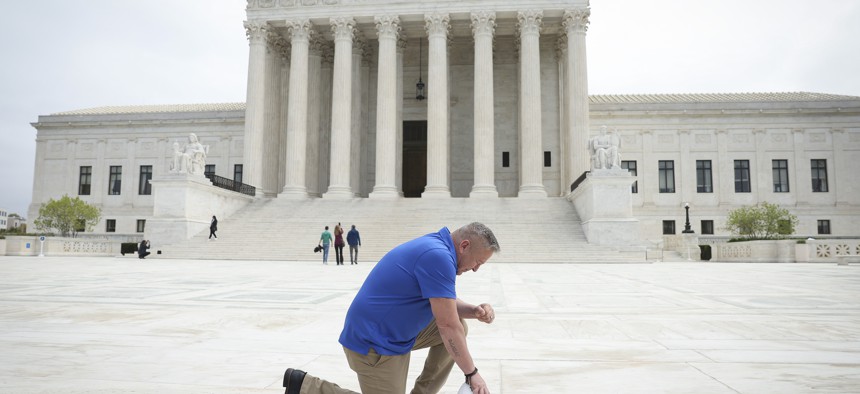 Former Bremerton High School assistant football coach Joe Kennedy takes a knee in front of the U.S. Supreme Court after his legal case, Kennedy vs. Bremerton School District, was argued before the court on April 25, 2022 in Washington, D.C.