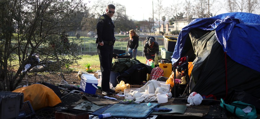 A Concord, California, police officer walks through a homeless encampment.