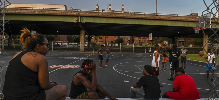 Kids play basketball at Wilson Park near where highway I-81 slices through the public housing complex called Pioneer Homes in the south side of Syracuse, N.Y., in 2019.