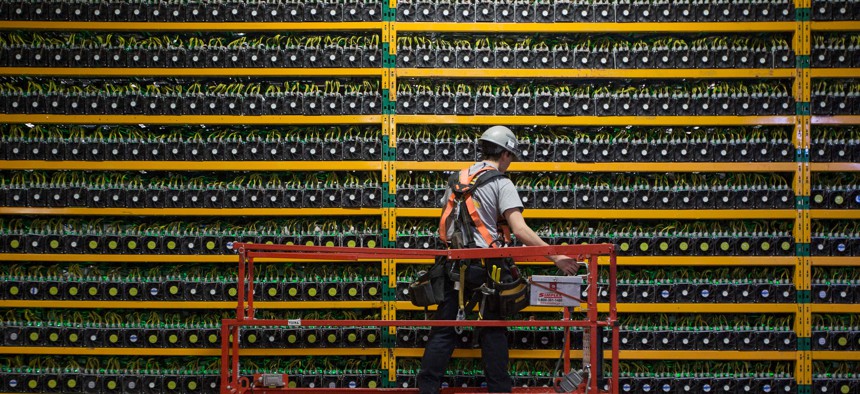 A technician inspects the backside of bitcoin mining at Bitfarms in Saint Hyacinthe, Quebec on March 19, 2018.