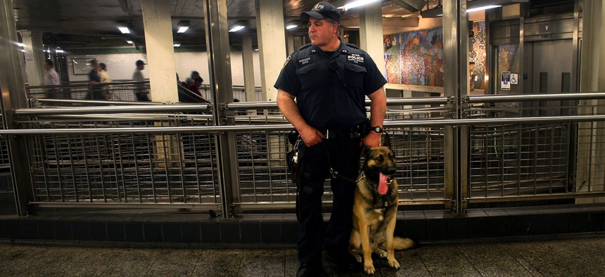 A police officer and his dog, Buster, watch pedestrians in the subway station in New York City.