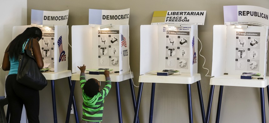 Aljinee Brunson, 24, goes over ballot while her 2-year-old son explore other voting booth at Douglas F. Dollarhide Community Center on Tuesday morning June 07, 2016 in Compton, California. 