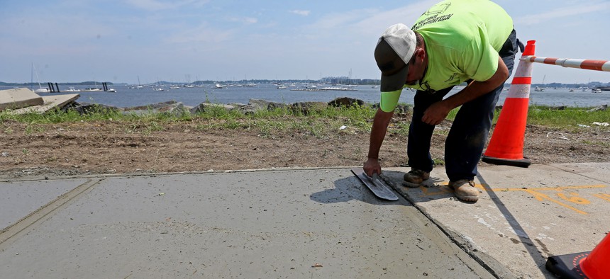 Lone construction worker John Goncalves, puts the finishing touches on the sidewalk along Morrissey Blvd as temperatures rise into the high 80s on July 6, 2021 in Dorchester, Boston, MA.