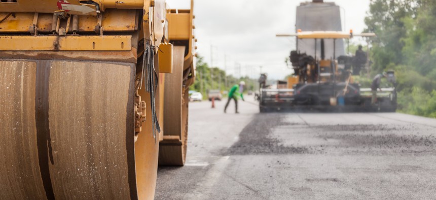 Road construction works with roller compactor machine and asphalt finisher.