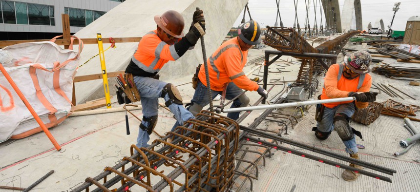Three ironworker rodbusters twist rebar for a barrier wall during the construction of the new 6th Street Bridge on May 17, 2022 in Los Angeles, California. 
