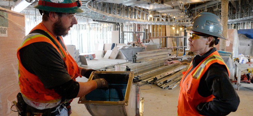 Instructor talks with first-year apprentice at construction site in Denver, Colo.
