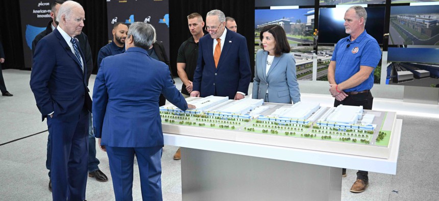 President Biden, with U.S. Senate Majority Leader Chuck Schumer, and New York Governor Kathy Hochul, looks at a 3D rendering of a future Micron factory presented by CEO of Micron Technology, Sanjay Mehrotra, during a tour of the Micron Pavilion at the SRC Arena and Events Center of Onondaga Community College in Syracuse, New York on Oct. 27, 2022.