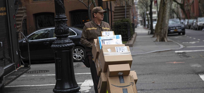 A delivery man for United Parcel Service, UPS, moves his hand truck loaded with packages through a residential neighborhood in Brooklyn, New York.